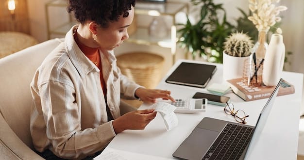A person sitting at a desk, making notes on a notepad while researching credit card interest rates on a laptop.
