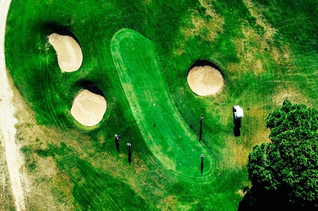 An aerial view of a lush green golf course with a few golfers in the distance, symbolizing leisure and long-term financial planning for retirement and estate purposes.