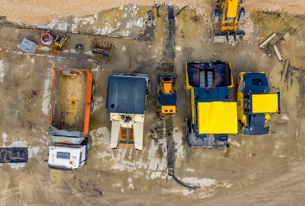 An aerial view of a construction site. Yellow bulldozers and other heavy equipment are on the site in different stages of construction.