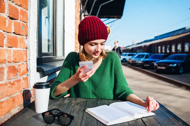 A student sitting at a cafe in a foreign city, studying notes and sipping coffee while observing the local culture around them. The image should highlight the combination of academic pursuit and cultural immersion.