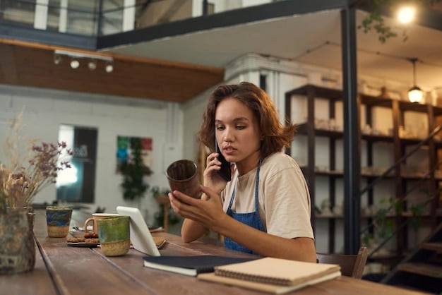 A freelancer working on their laptop at a coffee shop, showcasing the typical work environment of a gig worker. They are using a budgeting app on their phone.