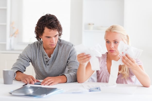 Two people, presumably a couple, sitting at a table reviewing financial documents together, representing the importance of coordination when claiming social security benefits.