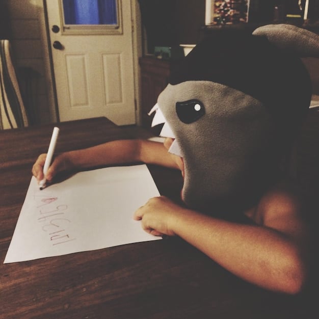 A close-up of a student writing an essay, with a pen in hand and a thesaurus open nearby. The focus is on the act of writing and the importance of thoughtful expression.