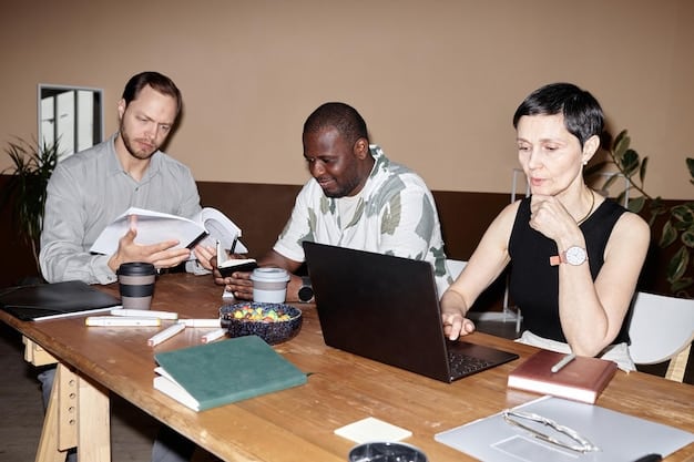 A diverse group of students gathered around a table in a college library, working together and discussing financial aid options from printed materials and laptops.