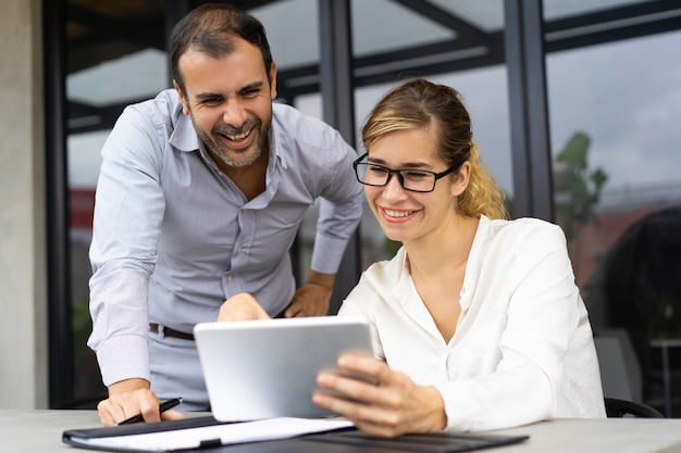 A horizontal shot of two business professionals in a modern office looking at a tablet and smiling.