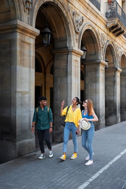 A diverse group of graduate students standing outside a university building, smiling and talking. The building has a traditional architectural style, with ivy climbing up the walls.