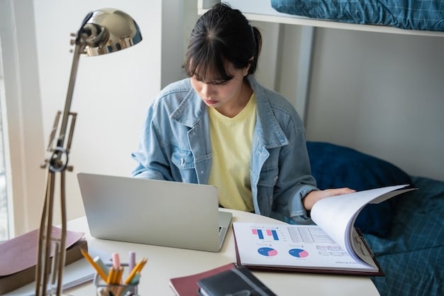 A student studying at a desk with a laptop. The screen displays a graph illustrating asset allocation and financial planning. Books related to finance and economics are stacked nearby.